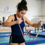 Vibrant rhythmic gymnastics rope coiled on a polished hardwood gym floor.