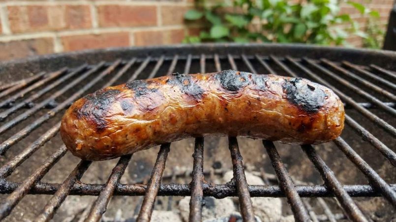 Simmering fresh pork sausages gently inside skillet water bath